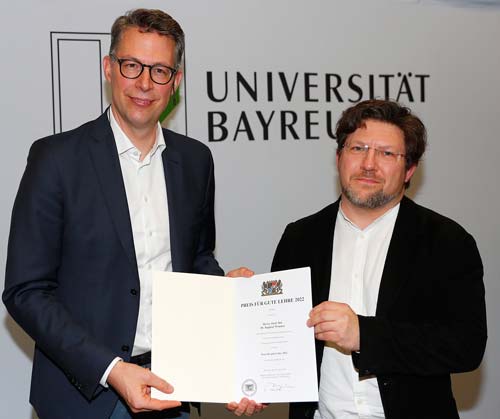 Dr. Raphael Wimmer erhält den „Preis für gute Lehre 2021“ von Wissenschaftsminister Markus Blume. (Foto: © Peter Kolb)