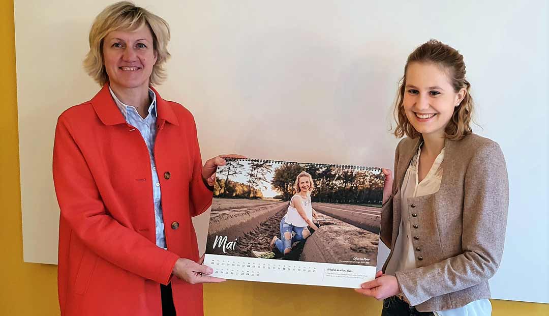 Spargelkönigin Katharina Maier (r.) überreicht Petra Högl den ersten Bayerischen Produktköniginnenkalender 2022 (Foto: Stefan Scheuerer)