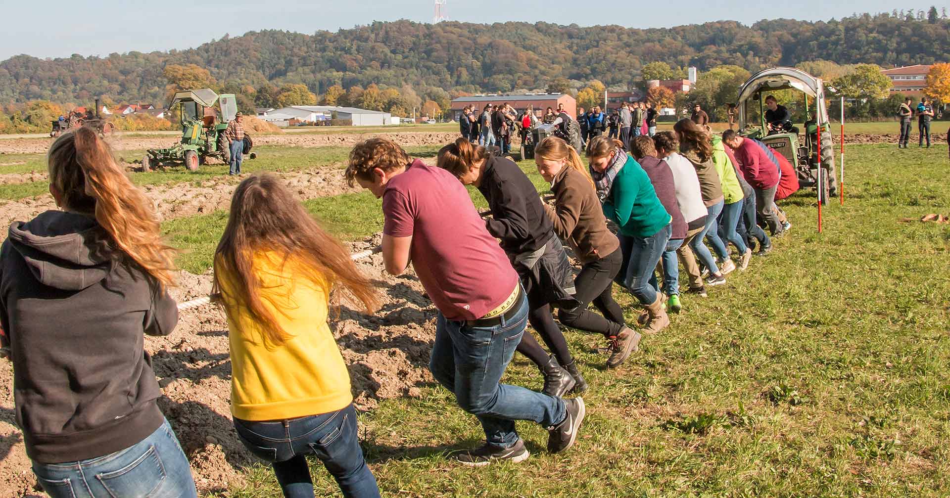 30 Studierende ziehen an einem Strang, um einen kleinen Schlepper samt Pflug in Bewegung zu bringen. (Foto: Bezirk Niederbayern/Bäter)